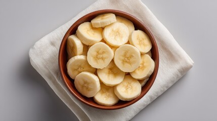 Poster - Top view of banana slices in a bowl on a white napkin, with empty space to the side for design