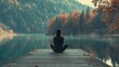 © Wattana - A woman meditating on a wooden dock by a calm lake with autumn foliage in the background.
