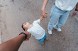 © ME Image - Asian toddler throwing a tantrum while holding hands with parents on a zoo outing. The child leans back dramatically, refusing to leave, showing real family life and parenting challenges.