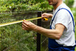 © ronstik - fencing services. worker taking measurements with measuring tape for new fence