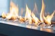© JIALU - Close-up of rectangular transparent glass fire pit with visible flames in modern minimalist style against white wall