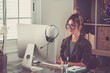 © simona - Professional young woman working in modern office with laptop and desktop computer – focused business environment, digital work, smart working and technology concept