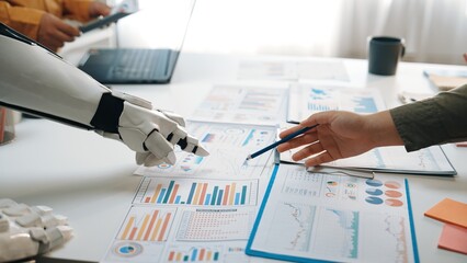 Poster - A human and robot collaborate in a modern office environment, engaging in data analysis with financial charts and reports on the table, showcasing innovation.Noogenesis