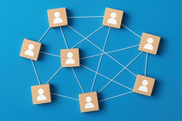 Poster - Networking Concept: Wooden blocks symbolizing people are interconnected by strings, representing a network or connection. The concept is displayed against a vibrant blue background.