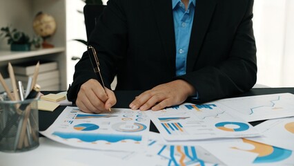 Poster - A focused businessman works on analyzing financial reports and charts at an organized office desk, showcasing professionalism and strategic planning.Noogenesis