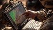 © Desmilka - A person's hand pointing at a map displayed on a rugged laptop computer.