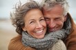 © Pavel - Joyful middle aged couple enjoying a warm hug on a breezy day at the beach with smiles that reflect their love and happiness