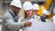 © THESUN - Construction workers with blueprint and safety helmets discussing project plan on site