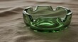 © Muhammad Wasil - A green glass ashtray sits on a textured beige fabric surface