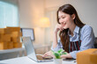 © Tj - Young entrepreneur woman managing her small business from a home office, checking orders on her laptop while smiling, showcasing the excitement of startup life and e-commerce success