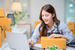 © Tj - Young asian woman entrepreneur, small business owner working at home office, online marketing packing boxes, SME seller prepare product for delivery to customers, startup online business concept