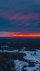 Wall Mural - vibrant red sunrise over snowy fields and bare trees in aerial hyperlapse, vertical