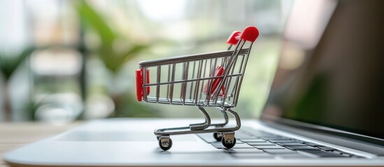 Poster - Miniature shopping cart resting on a laptop keyboard displaying online retail