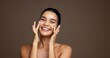 © Nina2025/peopleimages.com - Beauty, woman and happy with face cream in studio for collagen treatment, hydration and self care. Mockup, girl and cosmetics application on brown background for skin glow, anti aging and dermatology