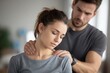 © ttonaorh - Young male physical therapist working with a female patient in a clinic office, holding her neck and shoulder for pain treatment at work.