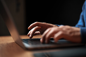Poster - Hands typing on a laptop in a dimly lit room during the evening hours