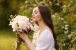 © New Africa - Beautiful woman with bouquet of peonies in park