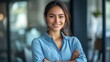 © COK House - Woman in office with a smile, standing confidently with arms crossed. Useful for articles on leadership and professional development.