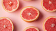 © Raden Mas Roy - Vibrant grapefruit halves arranged against a pastel pink backdrop creating fresh pattern