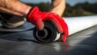 © Faadl - Roofing Worker Preparing a Roll of EPDM Roof Membrane Material, forces on hand closeup