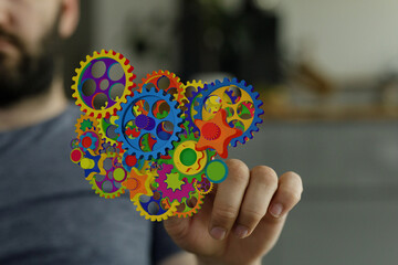 Poster - Abstract image of colorful gears on a finger, representing teamwork, innovation, and complex systems.