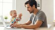 © Hamza - A man working on a laptop while his baby is clapping hands near him in a bright room with a window