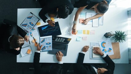 Poster - Top down aerial view of diverse business people discuss and brainstorm marketing idea while looking at financial graph at table with marketing document and sticky notes scatter around. Directorate.
