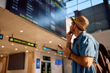 Male traveler checking his flight schedule at airport terminal.