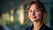 © Rifqi - Happy young female professional smiling confidently outside modern office building wearing stylish glasses represents success and confidence modern career woman junior executive