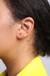 © New Africa - Young woman with pierced ear on light grey background, closeup