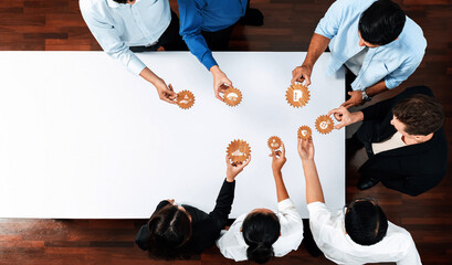 Poster - A diverse team engages in a collaborative meeting, sharing ideas represented by gear icons on a table. This interaction highlights effective management and innovative strategies. Amity