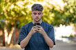 © carballo - young man in his 20s on the street looking at his cell phone