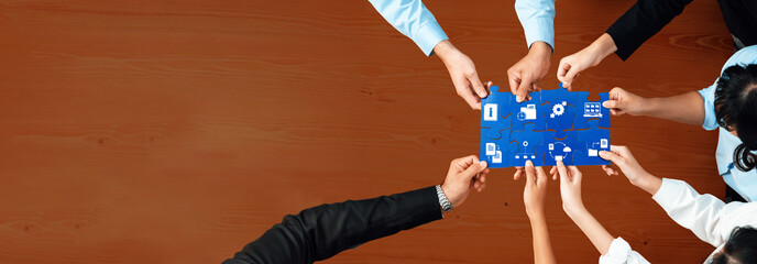 Poster - A diverse business team gathers around a blue puzzle piece filled with icons, symbolizing their collaborative efforts in management and strategic planning. Amity