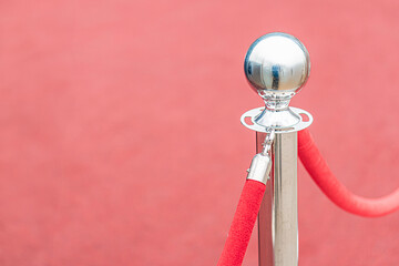 Poster - Red carpet, silver trophy on a rod, red velvet rope loop, possibly marking an exclusive area, gray background with subtle horizontal lines