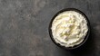© Chingiz - Top view of creamy ricotta cheese on a textured grey surface, space left for text