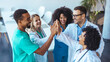 © Dragana Gordic - Group of Physicians Celebrating Teamwork With High Fives in a Modern Office