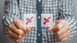 © top images  - A person in a plaid shirt holds two small white cards, each marked with a red X, suggesting rejection or a negative choice.