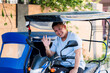 © Mdv Edwards - A cheerful tricycle driver sits on his vehicle and waves at the camera with a big, wide smile in a friendly gesture.