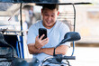 © Mdv Edwards - A smiling Southeast Asian tricycle driver sits in his vehicle while chatting on a video call, clearly engaged and enjoying the moment during a workday pause.