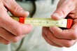 © Alfonmuseno - A close-up of a contractor's hands holding a measuring tape and marking construction materials, clean and professional composition, copy space, natural color, minimalism, stock photography