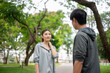 © bongkarn - Asian woman in sportswear smiling looking at man standing together after running on pavement in park