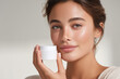 © Vitalii - Close-up portrait of a young woman with flawless skin holding a cosmetic cream jar