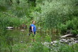 © Ольга Калинчук - A man crosses a river on rocks with a backpack.