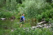 © Ольга Калинчук - A man crosses a river on rocks with a backpack.