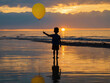 © MdSahid - Boy holding yellow balloon at sunset on beach child silhouette
