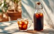 © aboutnuylove - Cold brew Glass bottle and glass of cola with ice cubes on table outdoors