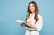 © ViDi Studio - Young successful employee business woman corporate lawyer she wears shirt formal clothes work in office hold clipboard sign paper account documents isolated on pastel blue background studio portrait.