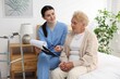 © New Africa - Nurse with clipboard examining senior woman indoors. Home health care service