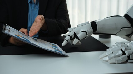 Poster - A robot hand interacts with a human during a business meeting, emphasizing innovation in data analysis and decision-making in a modern office setting.Noogenesis