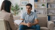 © Anastasiya - Young man sitting on sofa during counseling session in office